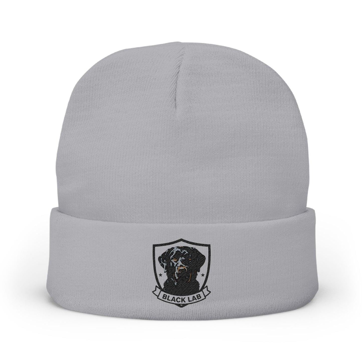A light gray knit beanie hat with a folded cuff, featuring a black and white graphic of a dog inside a shield with the text 'BLACK LAB' below it.