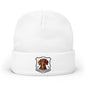 A white knit cuffed beanie hat featuring a shield-shaped Dachshund graphic on the front cuff.