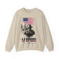 A beige crewneck sweatshirt featuring a graphic print of a German Shepherd, a K-9 officer in a helmet, a distressed American flag, and the text 'K-9 WARRIORS LOYAL BRAVE UNBREAKABLE' with 'SANNI CATHOLIC COLLECTIONT' printed below.