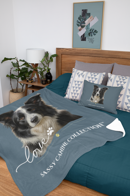 A personalized pet breed blanket and matching pillow (sold separately.) The blanket is slate blue with a large printed portrait of a black and white dog, accompanied by the word 'love' in white script and the text 'SASSY CANINE COLLECTION'.