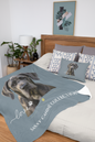 A pet-themed bedding set displayed on a bed in a styled bedroom (pillow sold separately.) The set includes a slate blue throw blanket with a large portrait of a Great Dane dog, white  text reading 'love SASSY CANINE COLLECTION'
