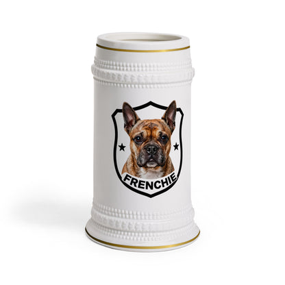 A white ceramic beer stein featuring a custom printed graphic of a French Bulldog inside a black shield with the word 'FRENCHIE' below it. The stein has gold trim at the rim and base, set against a plain white background.