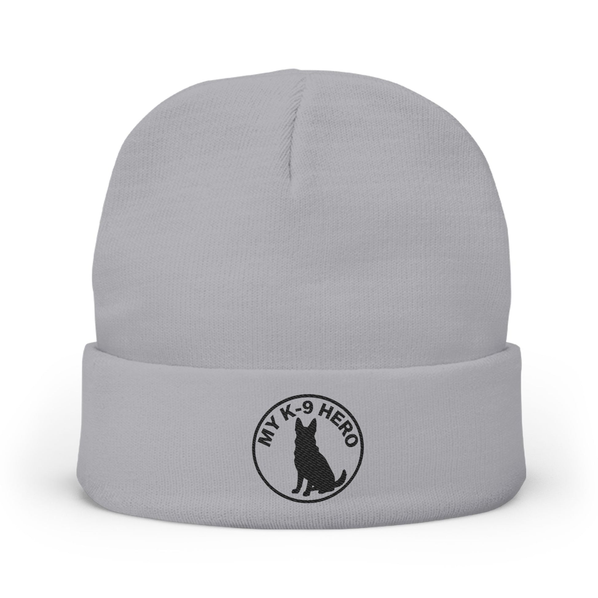 A light gray knit beanie hat with a folded cuff, featuring a black circular embroidered logo on the front that reads 'MY K-9 HERO' around a dog silhouette.