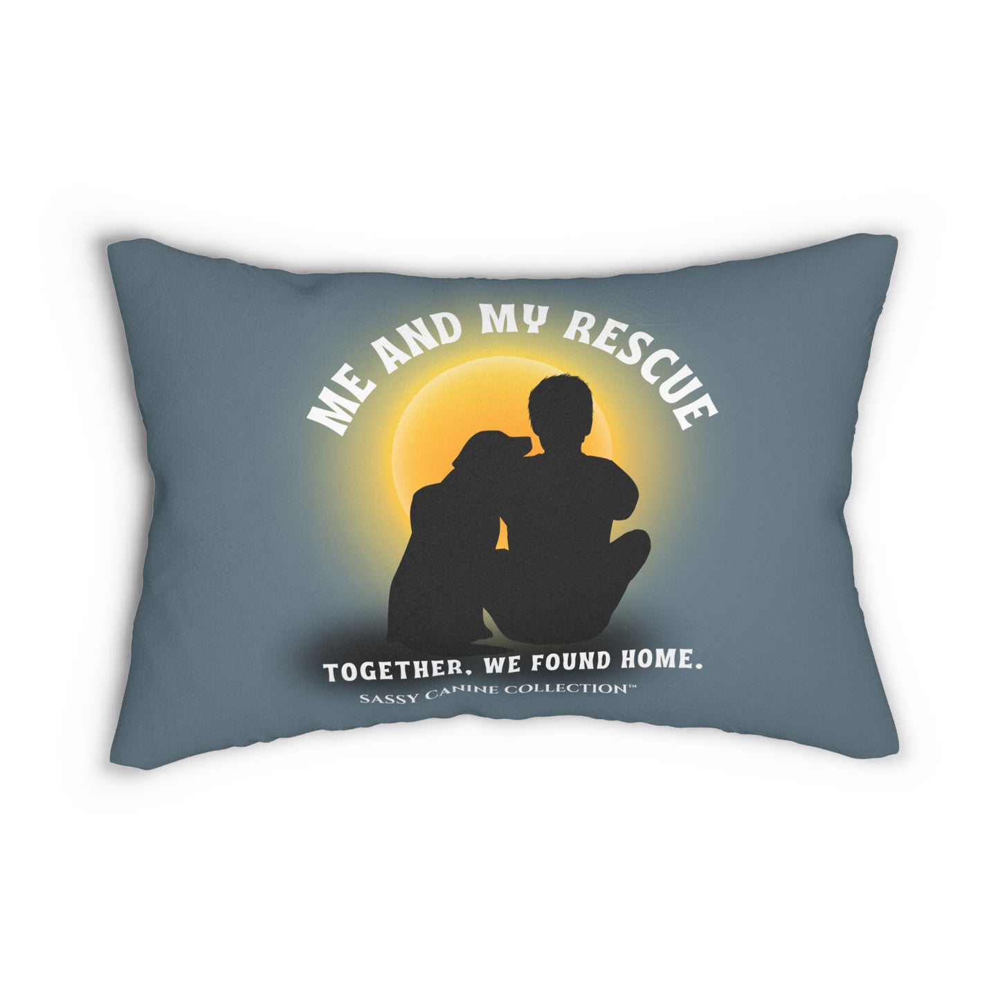 A lumbar throw pillow in slate blue with a printed graphic of a rescue dog and cat silhouette in front of a glowing yellow sun. White text reads 'ME AND MY RESCUE' above the silhouettes and 'TOGETHER, WE FOUND HOME.