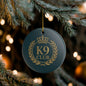 A round dark teal Christmas ornament with a gold 'K9 CLUB' 