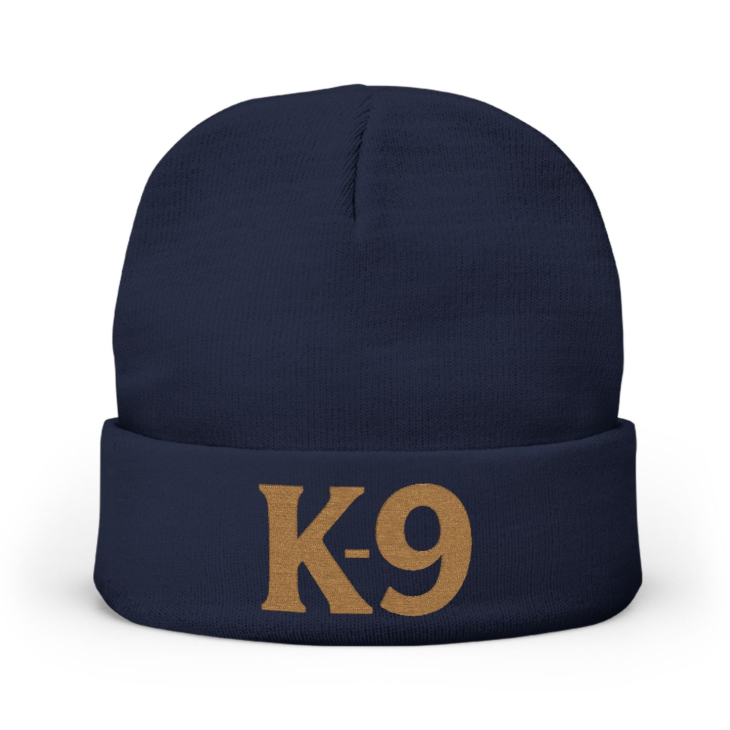 A navy blue knit beanie with a folded cuff featuring the text 'K-9' embroidered in a tan/gold color, shown against a plain white background.