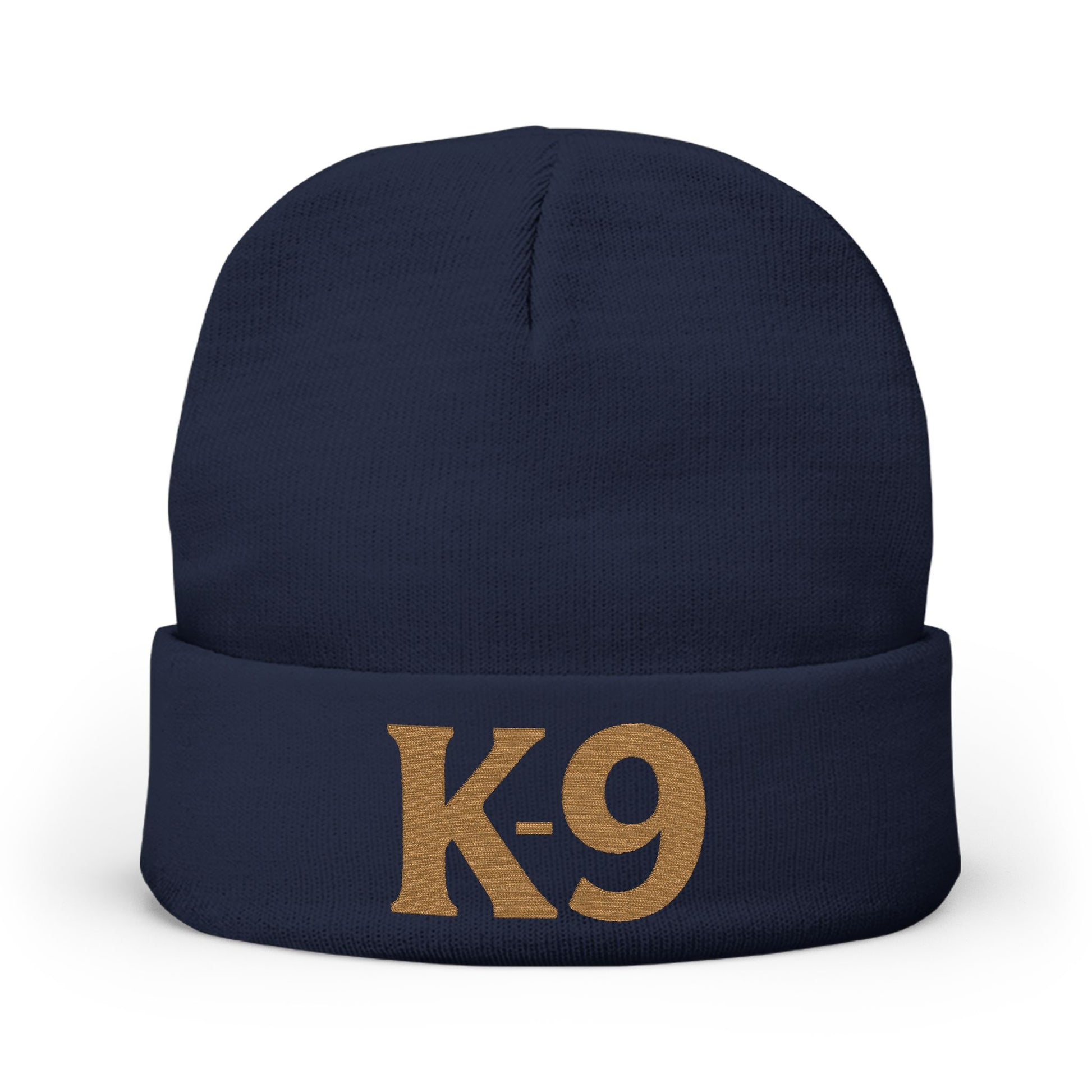 A navy blue knit beanie with a folded cuff featuring the text 'K-9' embroidered in a tan/gold color, shown against a plain white background.