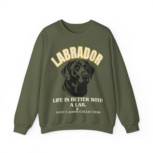 An olive green crewneck sweatshirt featuring a graphic print of a black Labrador dog with the text 'LABRADOR LIFE IS BETTER WITH A LAB.' and 'SASSY CANINE COLLECTION' in cream and gold lettering.
