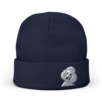 A navy blue knit beanie hat featuring a small embroidered white poodle on the front cuff