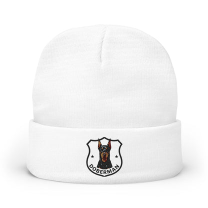 A white knit cuffed beanie hat featuring a printed Doberman dog crest logo on the front cuff.