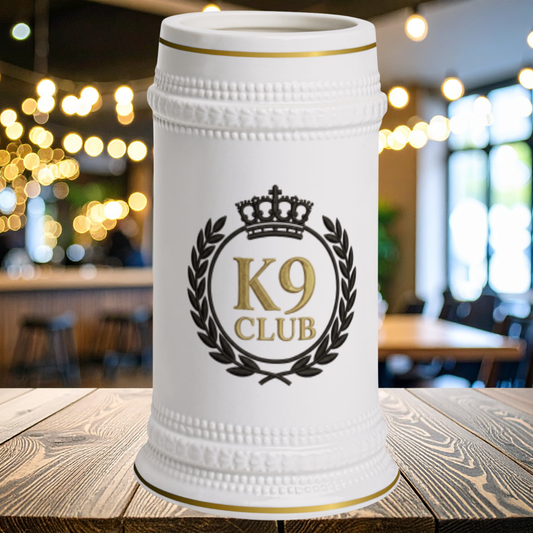 A white ceramic beer stein with gold and black detailing, featuring a 'K9 CLUB' emblem with a crown and laurel wreath