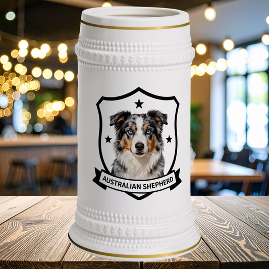 A white ceramic beer stein with gold trim and a portrait of a  Australian Shepherd dog 